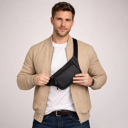 Man draagt zwarte leren heuptas crossbody over een beige jack