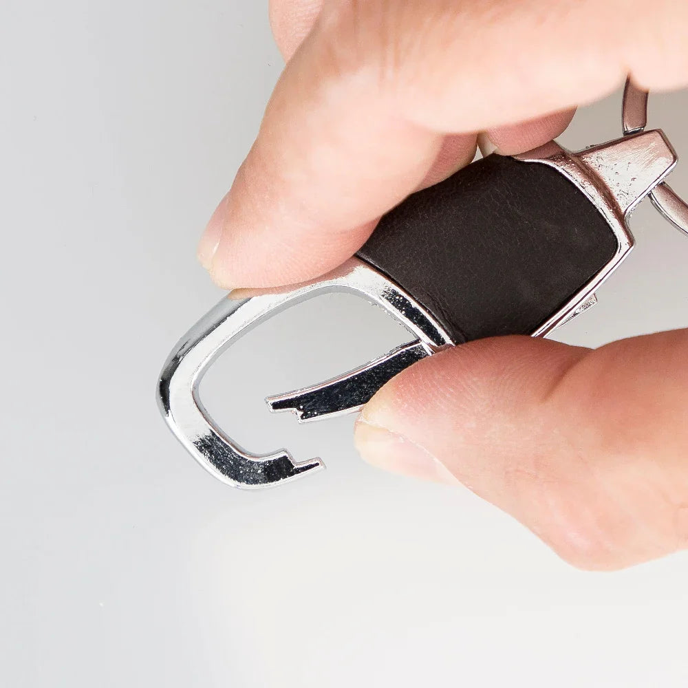 Donkerbruine leren sleutelhanger in de hand met geopende karabijnhaak