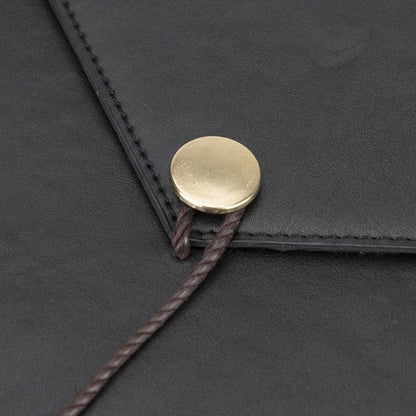 Detail van de metalen knoop en het leren koordje op de laptophoes