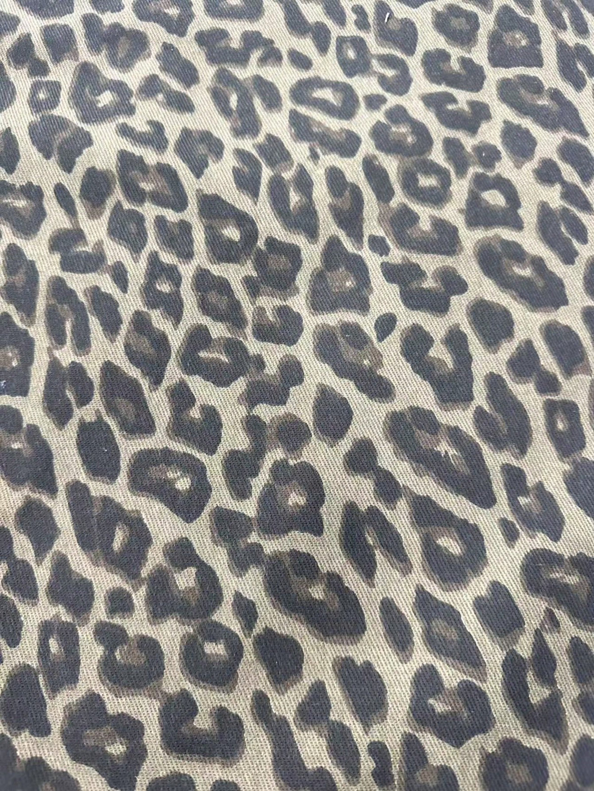 Detail van de luipaardprint op zandkleurig denim