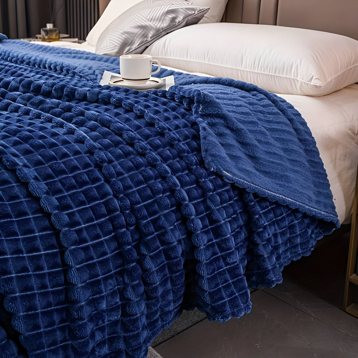 Fleece deken van koraalfleece met blokjesreliëf over een bed - koningsblauw