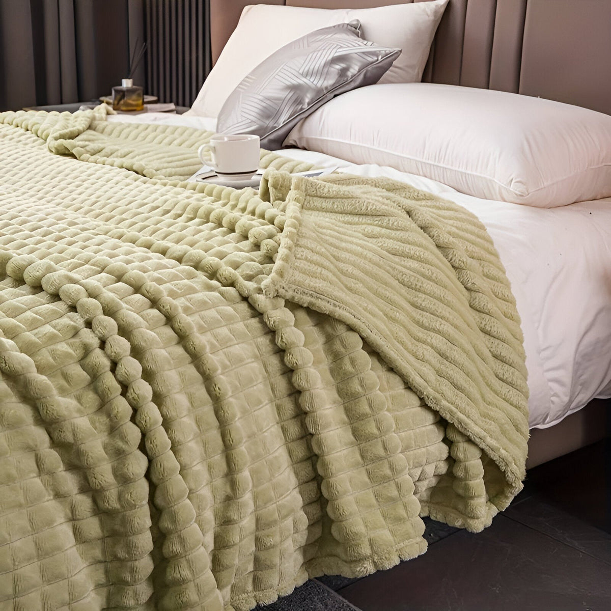 Fleece deken van koraalfleece met blokjesreliëf over een bed - pistachegroen