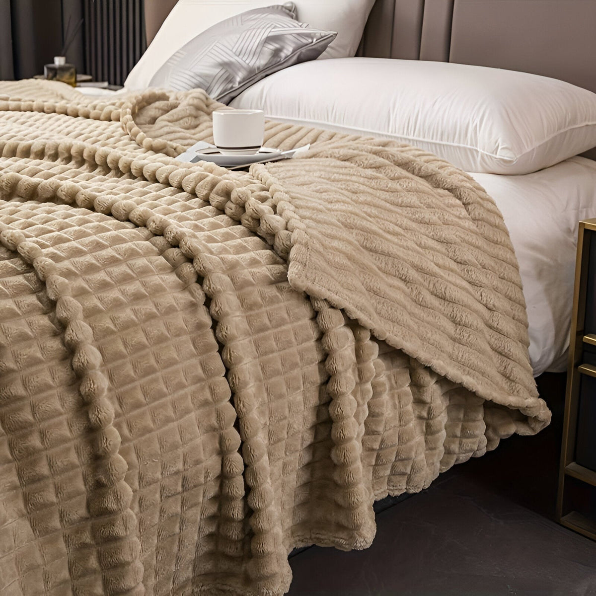 Fleece deken van koraalfleece met blokjesreliëf over een bed - kameel