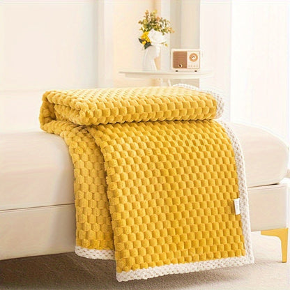 Fleece plaid met blokreliëf en een gebreide rand over de rand van een bed - geel