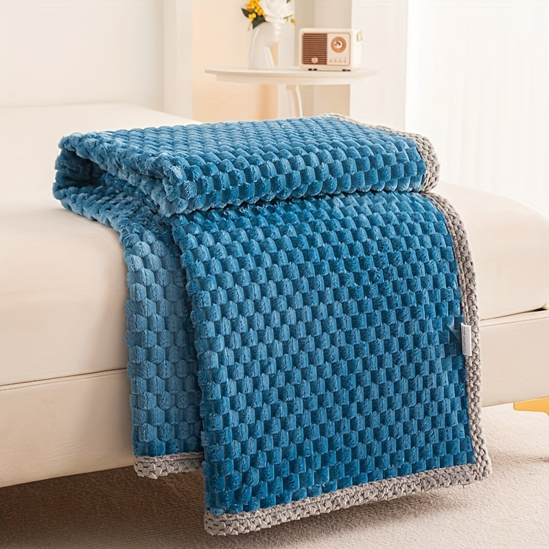 Fleece plaid met blokreliëf en een gebreide rand over de rand van een bed - blauw
