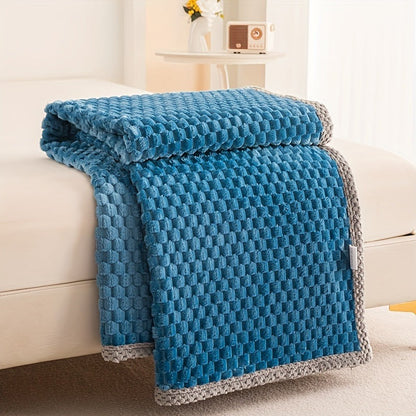 Fleece plaid met blokreliëf en een gebreide rand over de rand van een bed - blauw