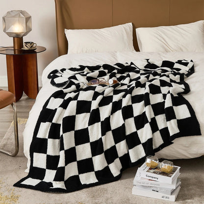 Gebreide plaid van teddy met dambordpatroon over een fauteuil - zwart