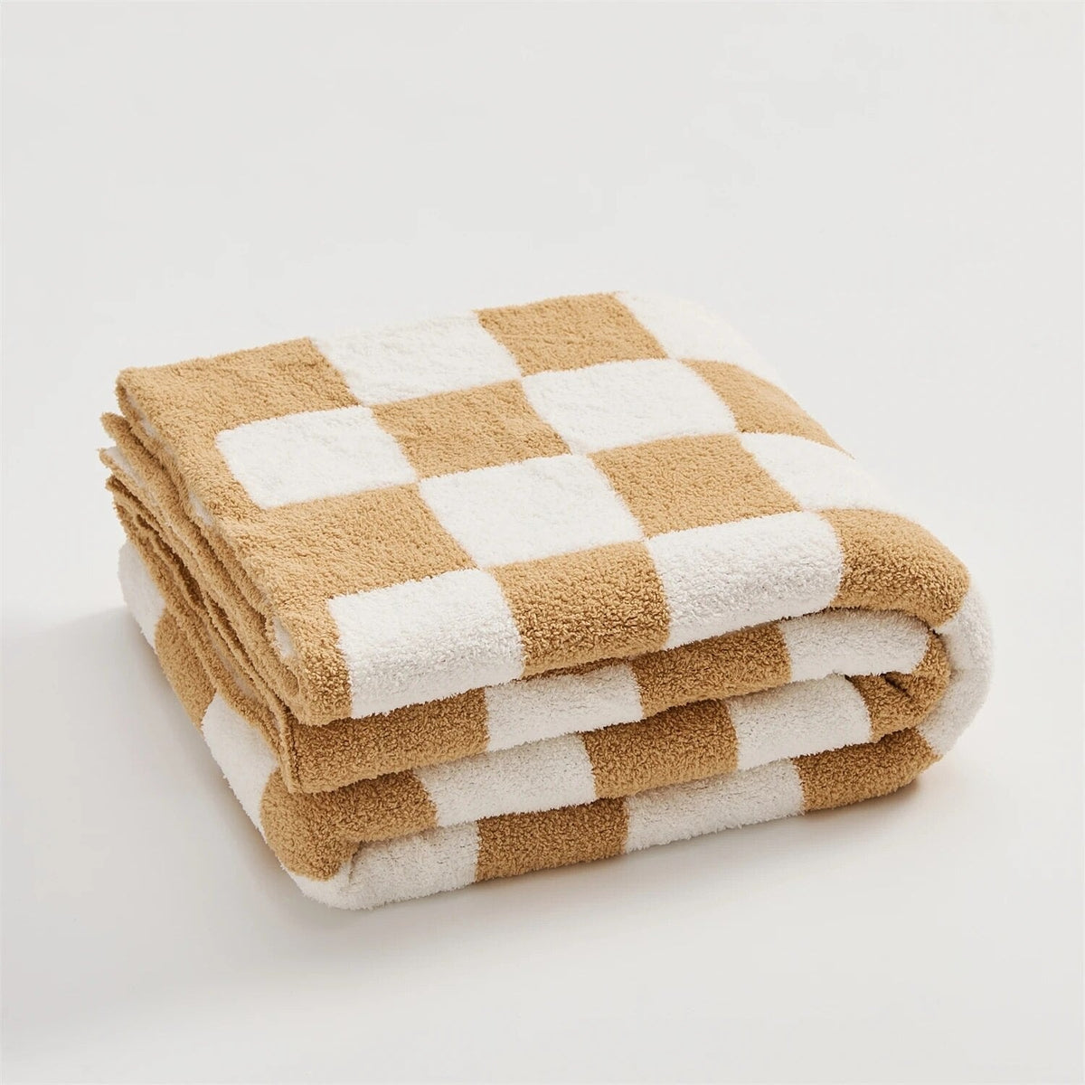 Gebreide plaid van teddy met dambordpatroon over een fauteuil - karamel