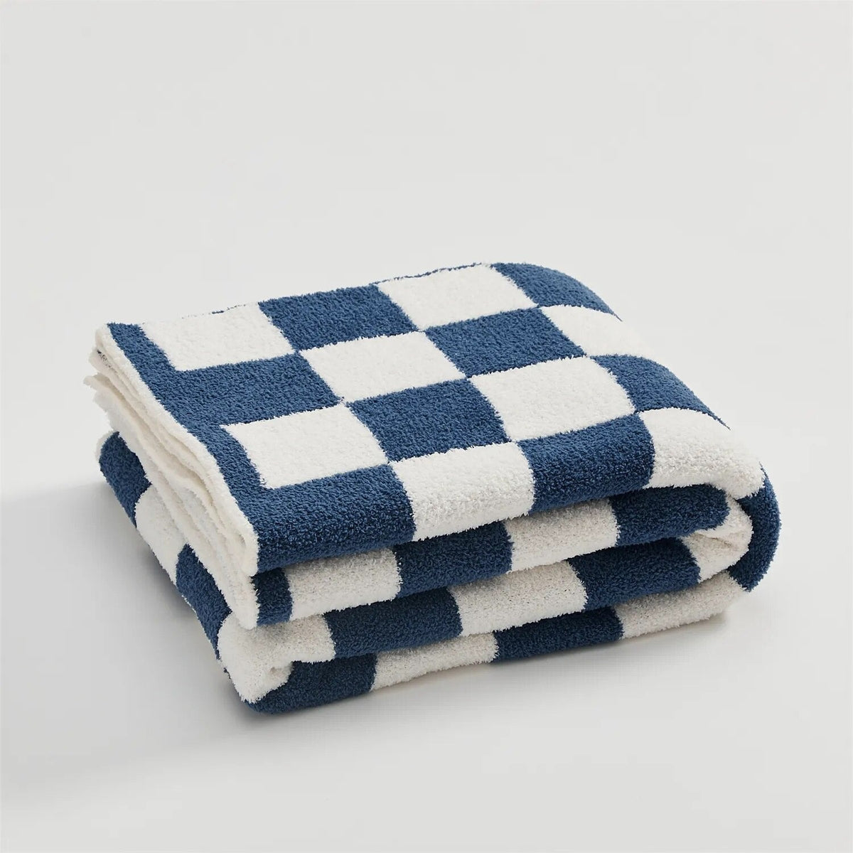 Gebreide plaid van teddy met dambordpatroon over een fauteuil - marineblauw