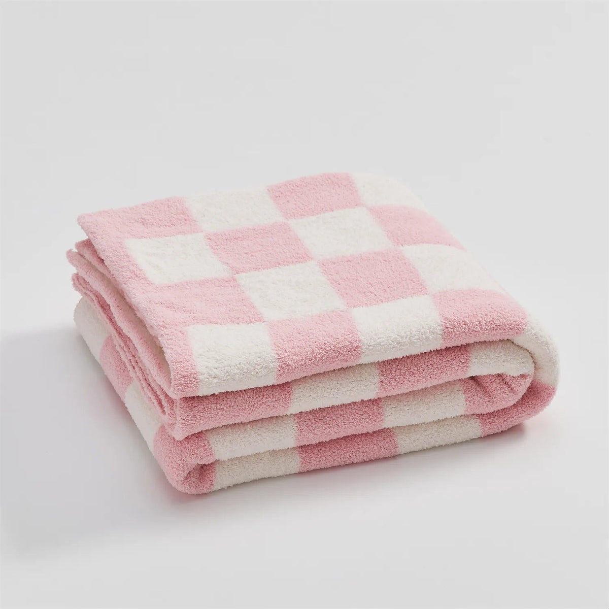 Gebreide plaid van teddy met dambordpatroon over een fauteuil - roze