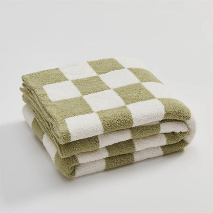 Gebreide plaid van teddy met dambordpatroon over een fauteuil - saliegroen