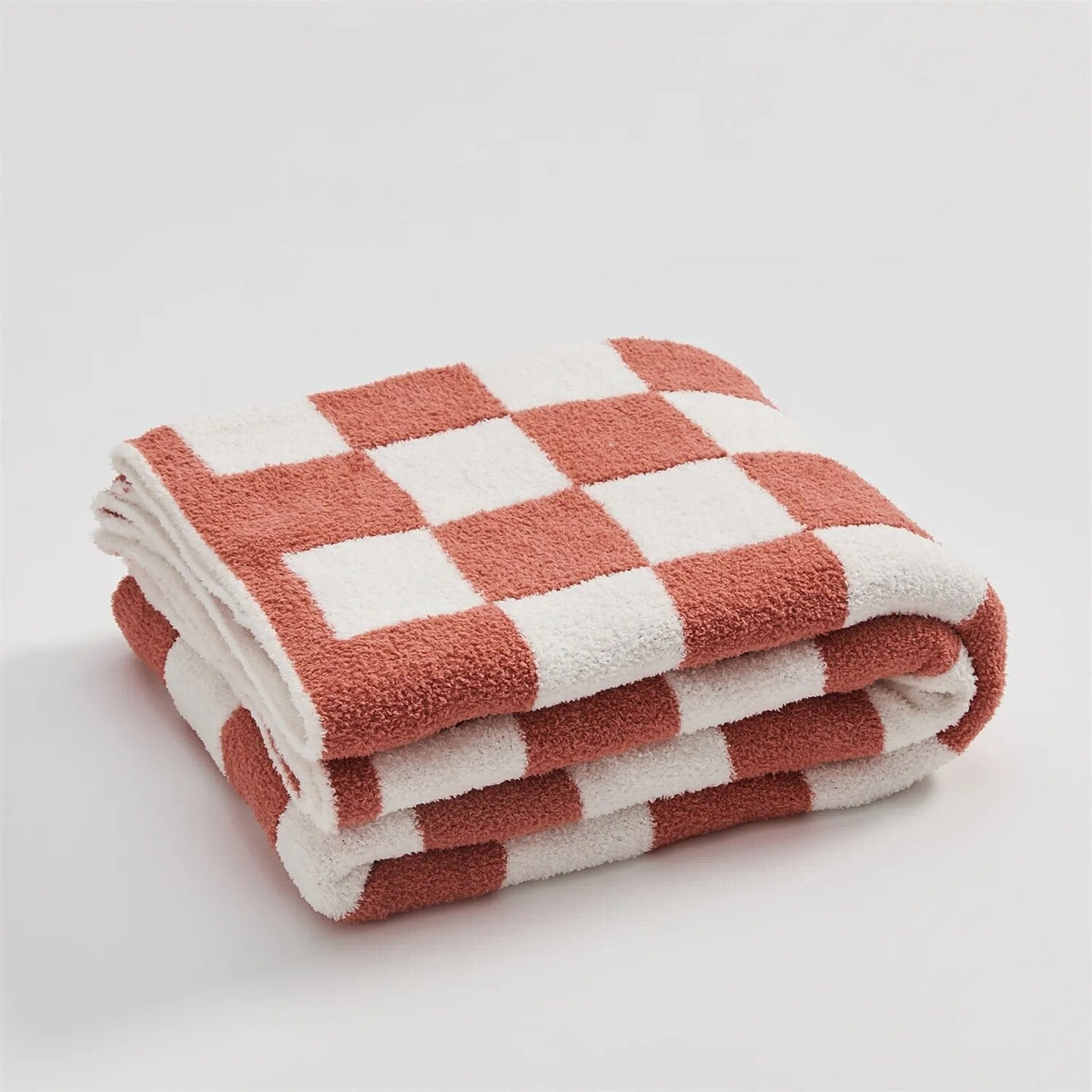 Gebreide plaid van teddy met dambordpatroon over een fauteuil - koraalrood