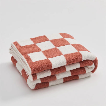 Gebreide plaid van teddy met dambordpatroon over een fauteuil - koraalrood