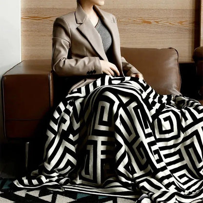 Gebreide plaid met geometrisch patroon over een bruine bank - zwart