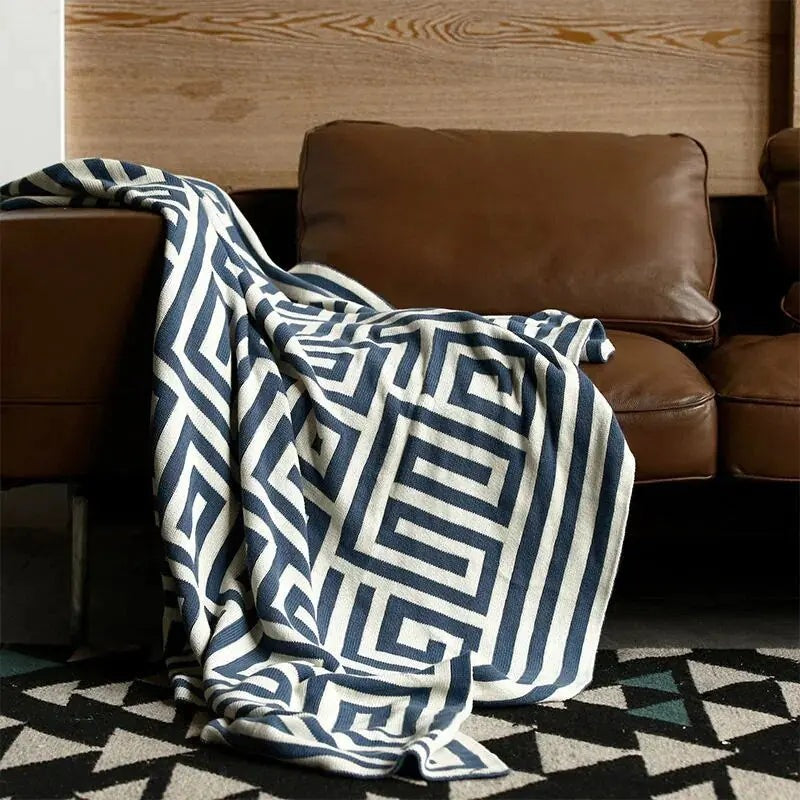 Gebreide plaid met geometrisch patroon over een bruine bank - marineblauw