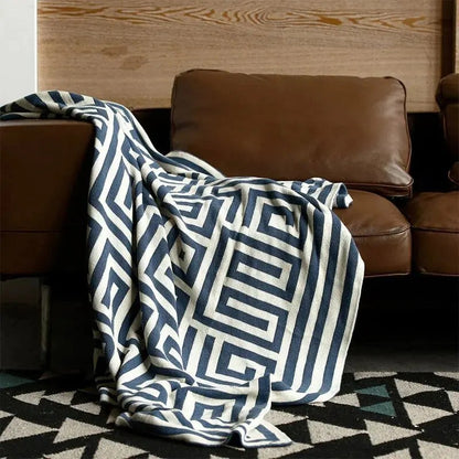 Gebreide plaid met geometrisch patroon over een bruine bank - marineblauw