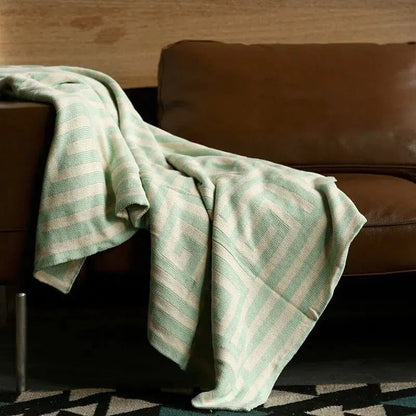 Gebreide plaid met geometrisch patroon over een bruine bank - mintgroen