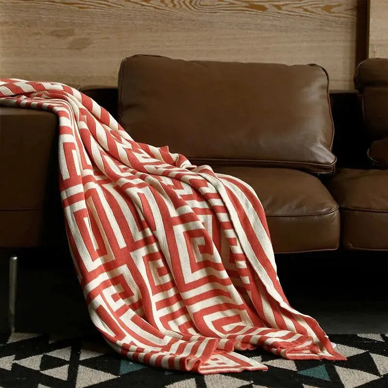 Gebreide plaid met geometrisch patroon over een bruine bank - roest