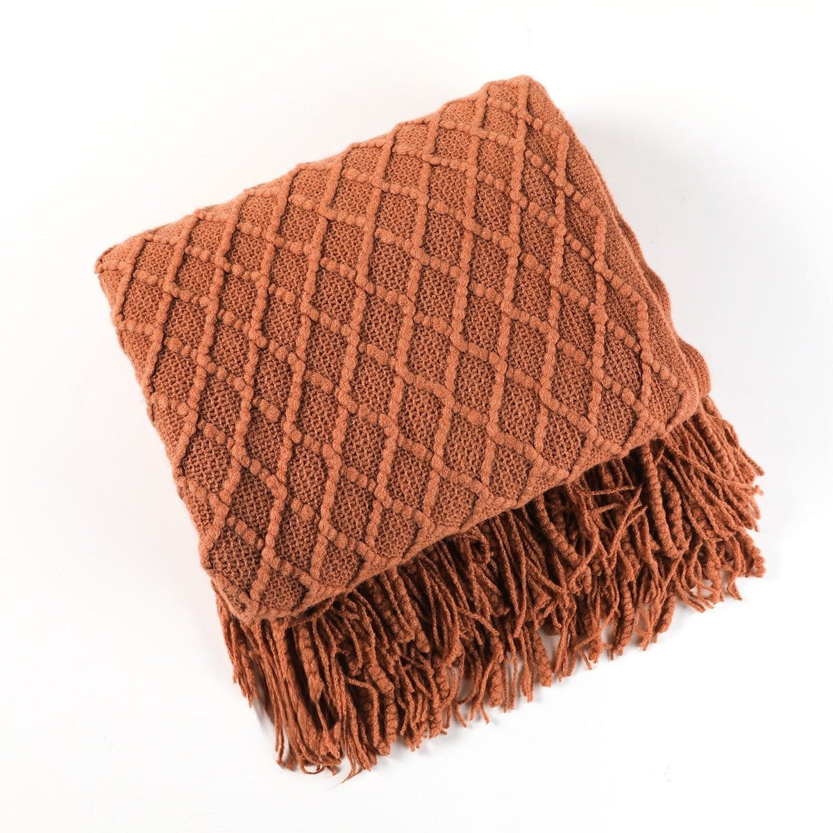 Gebreide plaid met Scandinavisch patroon en franjes over een stoel - terracotta