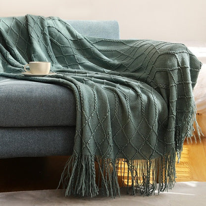 Gebreide plaid met Scandinavisch patroon en franjes over een stoel - donkergroen