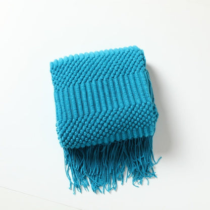 Gebreide plaid met Scandinavisch patroon en franjes over een stoel - turkoois