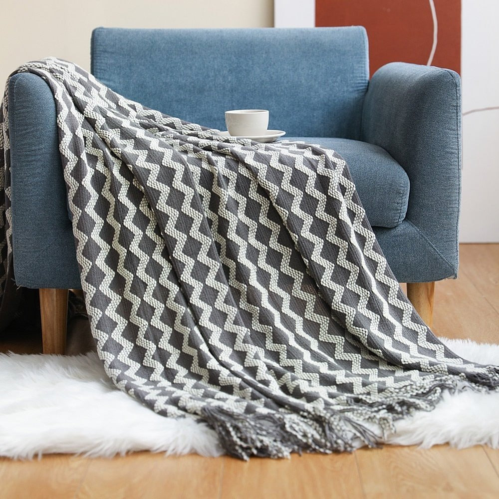 Gebreide plaid met Scandinavisch patroon en franjes over een stoel - grijs-wit zigzag