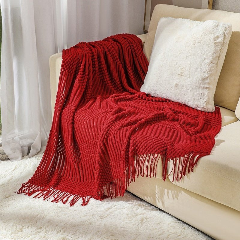 Gebreide plaid met Scandinavisch patroon en franjes over een stoel - rood