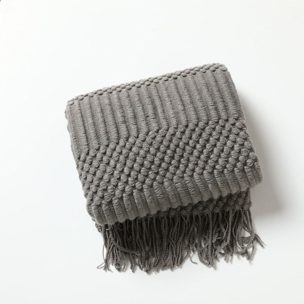 Gebreide plaid met Scandinavisch patroon en franjes over een stoel - grijs