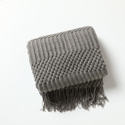 Gebreide plaid met Scandinavisch patroon en franjes over een stoel - grijs