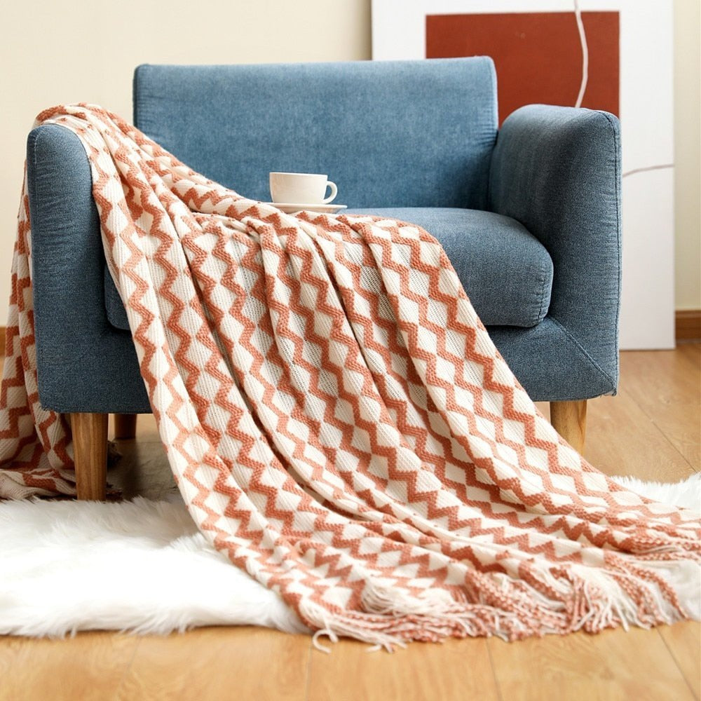 Gebreide plaid met Scandinavisch patroon en franjes over een stoel - zalmroze-wit zigzag