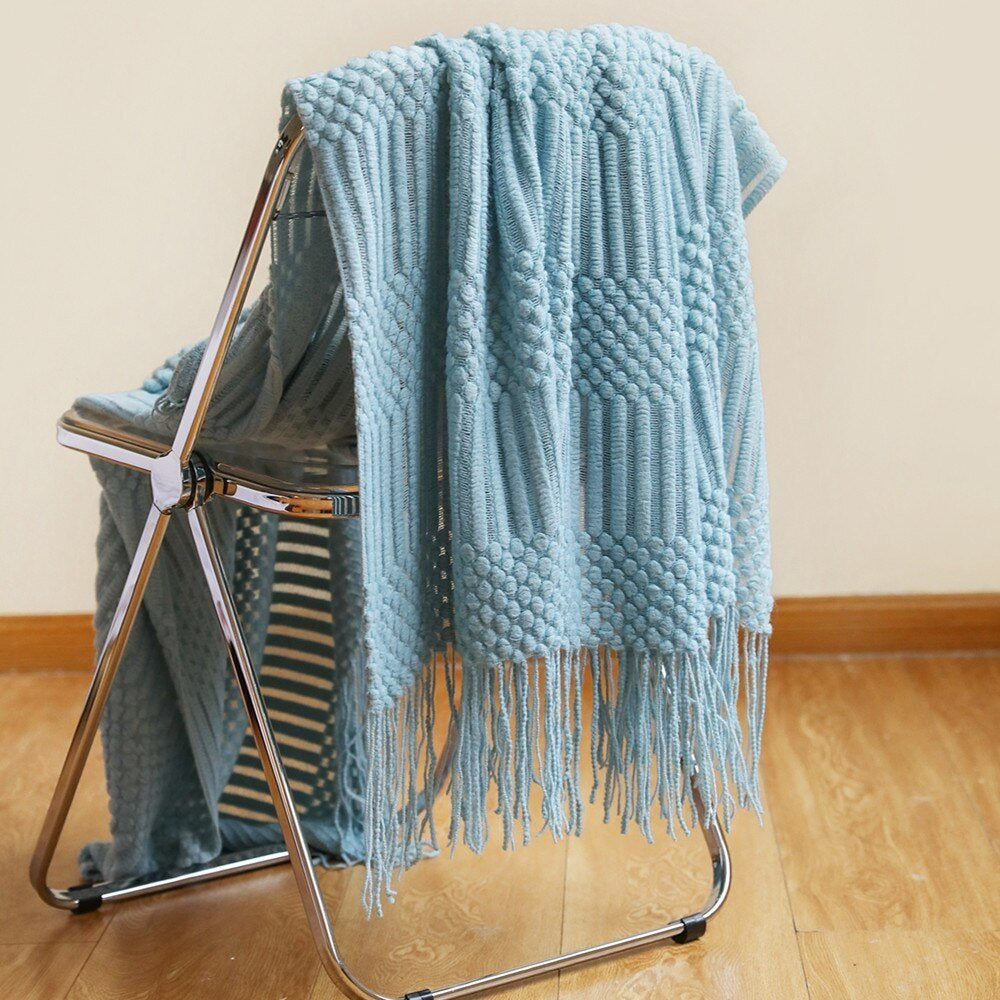 Gebreide plaid met Scandinavisch patroon en franjes over een stoel - lichtblauw