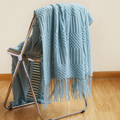 Gebreide plaid met Scandinavisch patroon en franjes over een stoel - lichtblauw