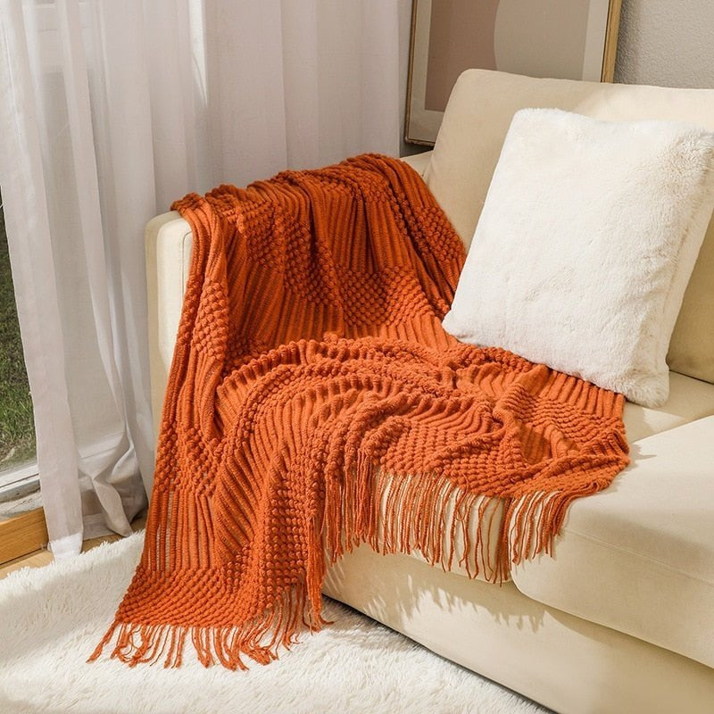 Gebreide plaid met Scandinavisch patroon en franjes over een stoel - oranje