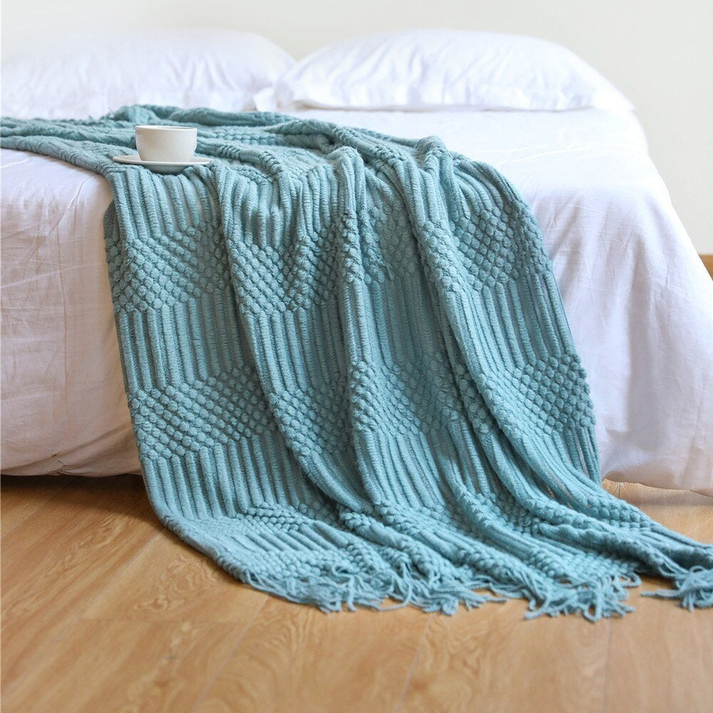 Gebreide plaid met Scandinavisch patroon en franjes over een stoel - aqua
