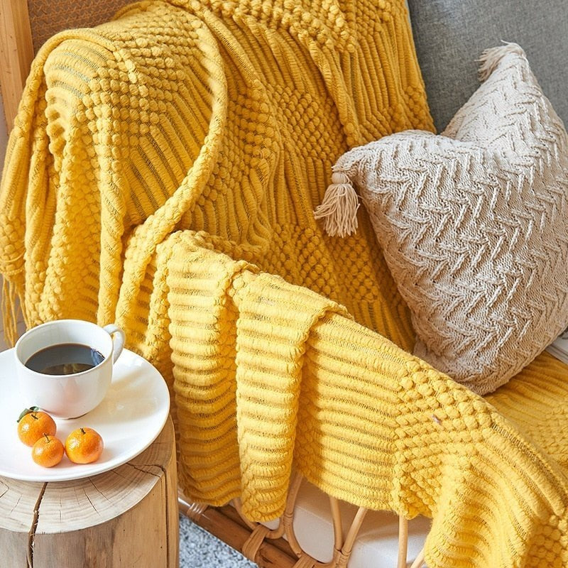 Gebreide plaid met Scandinavisch patroon en franjes over een stoel - geel