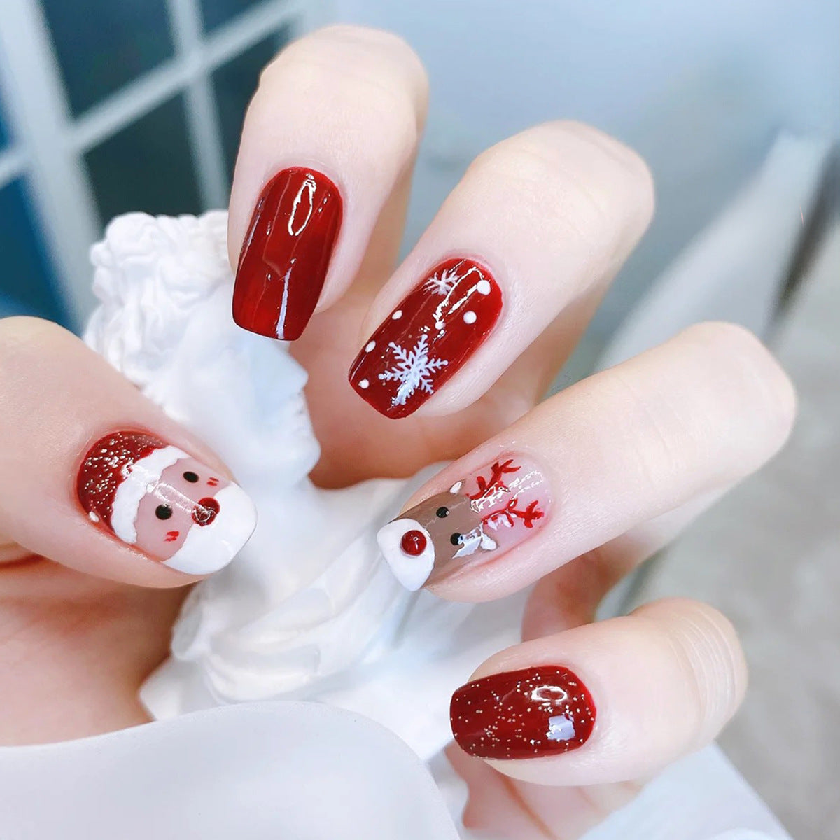 Kerst plaknagels met kerstprint, opgeplakt op een hand - rood met kerstman en rendier