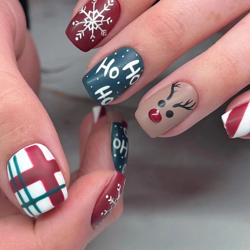 Kerst plaknagels met kerstprint, opgeplakt op een hand - ho ho ho met rendier en ruit