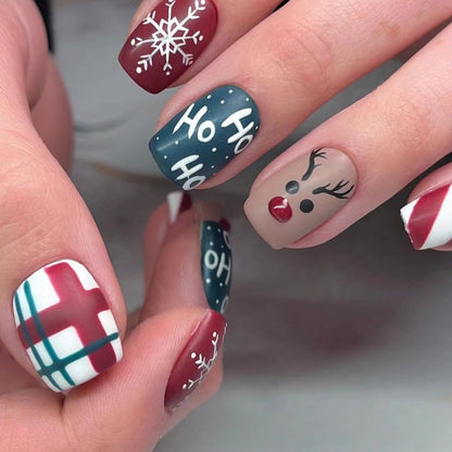 Kerst plaknagels met kerstprint, opgeplakt op een hand - ho ho ho met rendier en ruit
