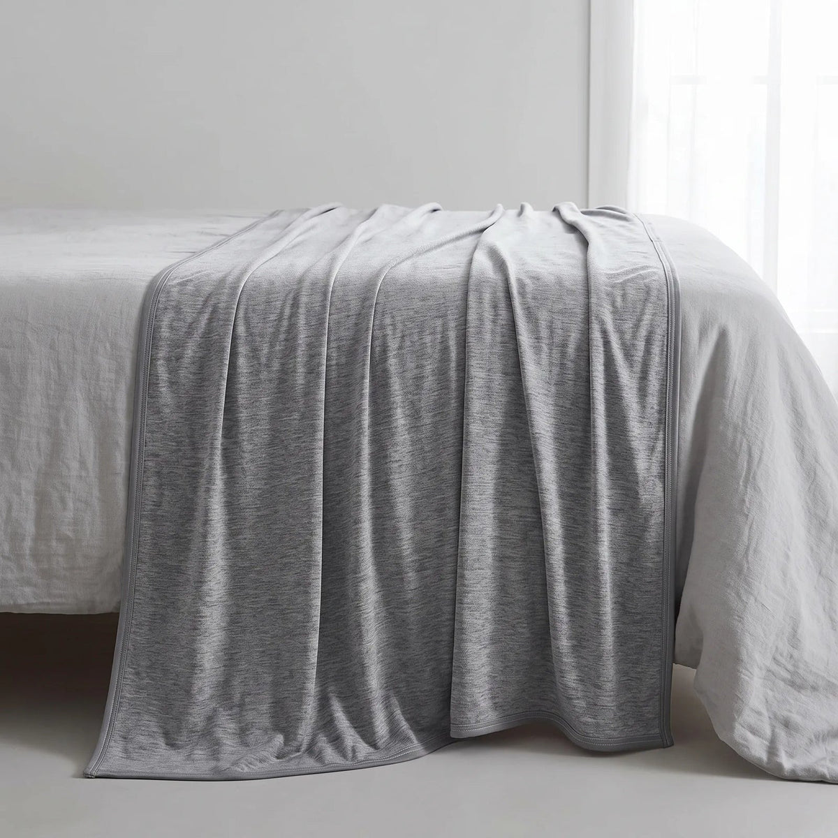 Dubbelzijdige koeldeken over een opgemaakt bed