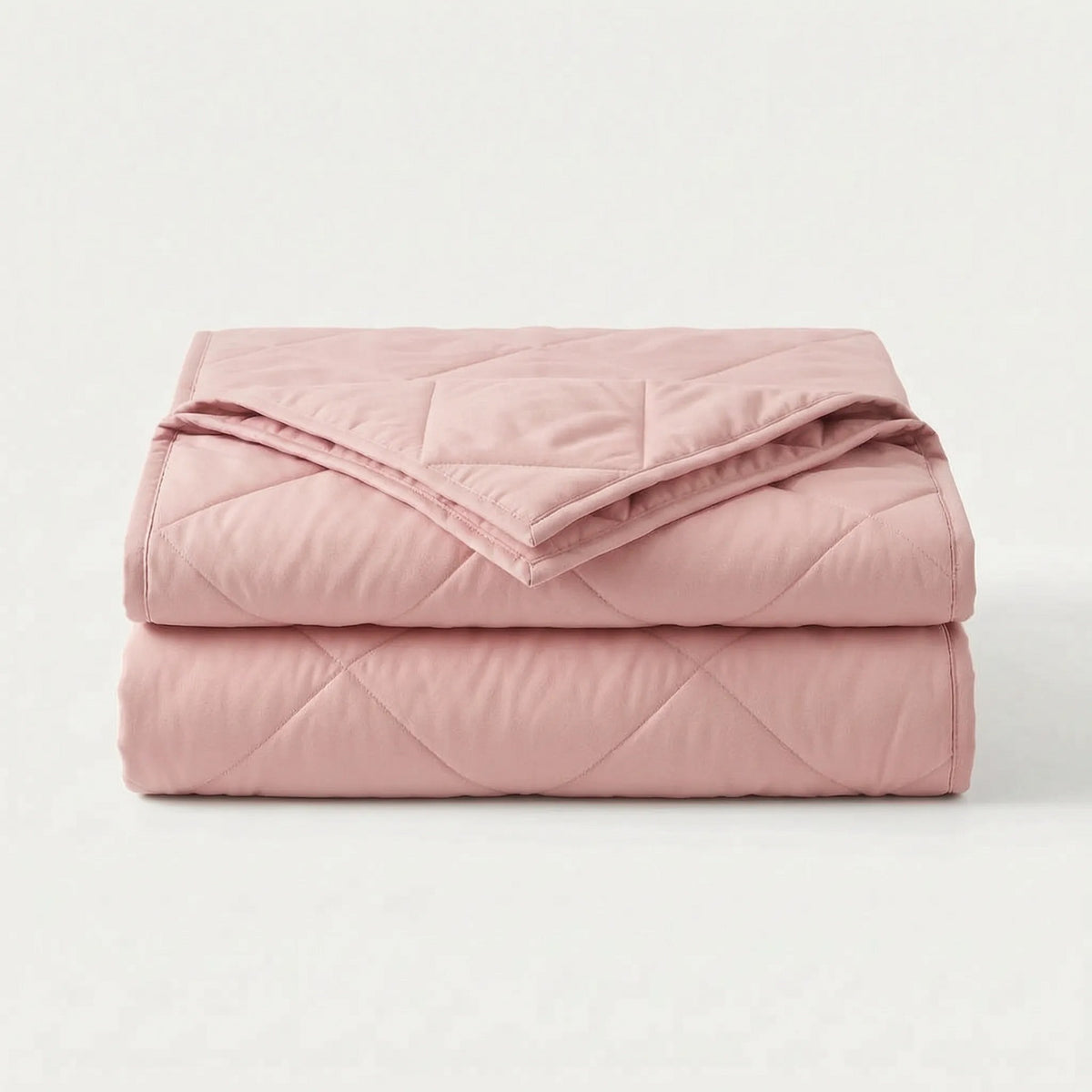 Lichte koeldeken met ruitstiksel over een opgemaakt bed - roze