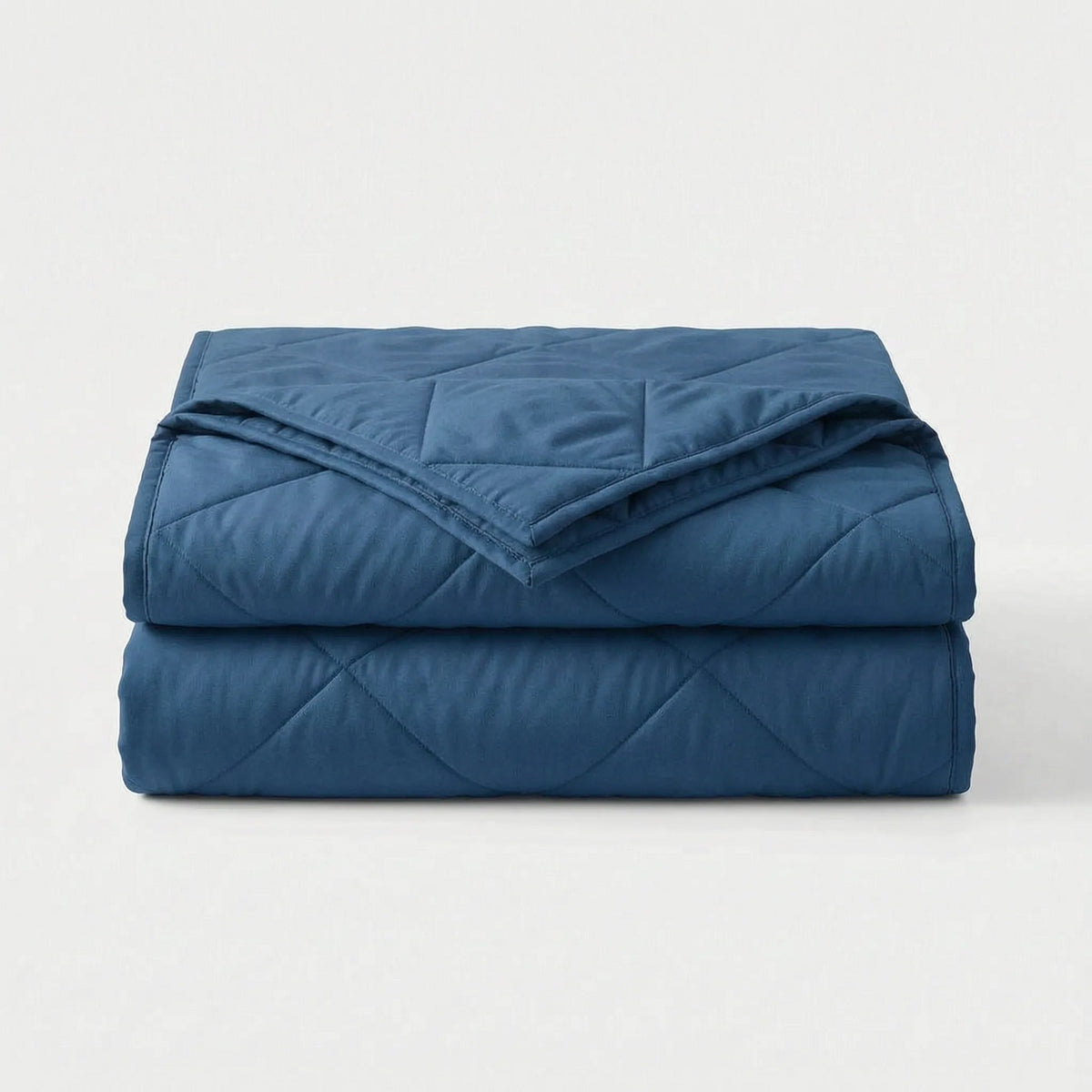Lichte koeldeken met ruitstiksel over een opgemaakt bed - donkerblauw