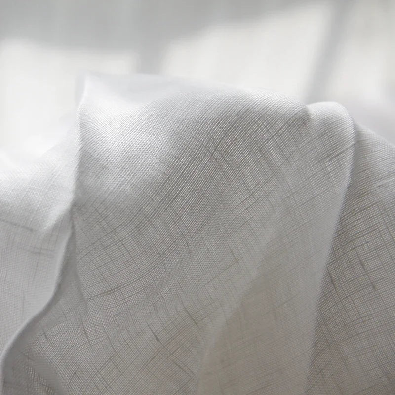 Luchtig geweven laken met gewassen look op een bed - wit