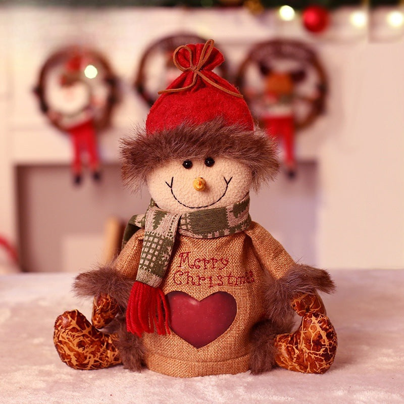 Zittend pluche kerstfiguur met muts, sjaal en een hartvormig venster in het lijfje - sneeuwpop
