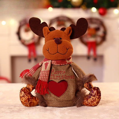 Zittend pluche kerstfiguur met muts, sjaal en een hartvormig venster in het lijfje - rendier