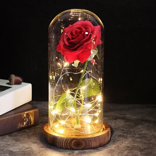 Kunstroos onder een doorzichtige stolp met LED-lichtsnoer om de steel, op een ronde houten voet - rood