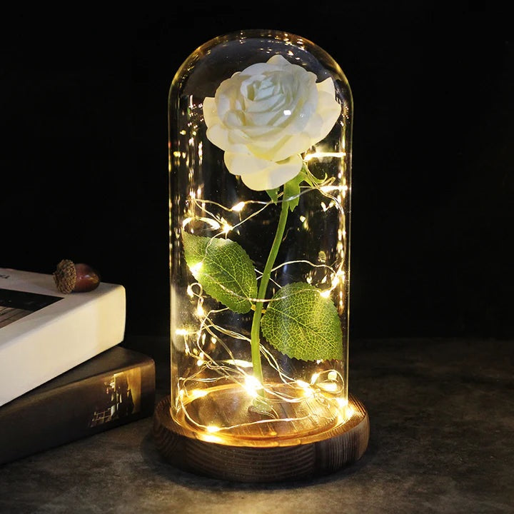 Kunstroos onder een doorzichtige stolp met LED-lichtsnoer om de steel, op een ronde houten voet - wit