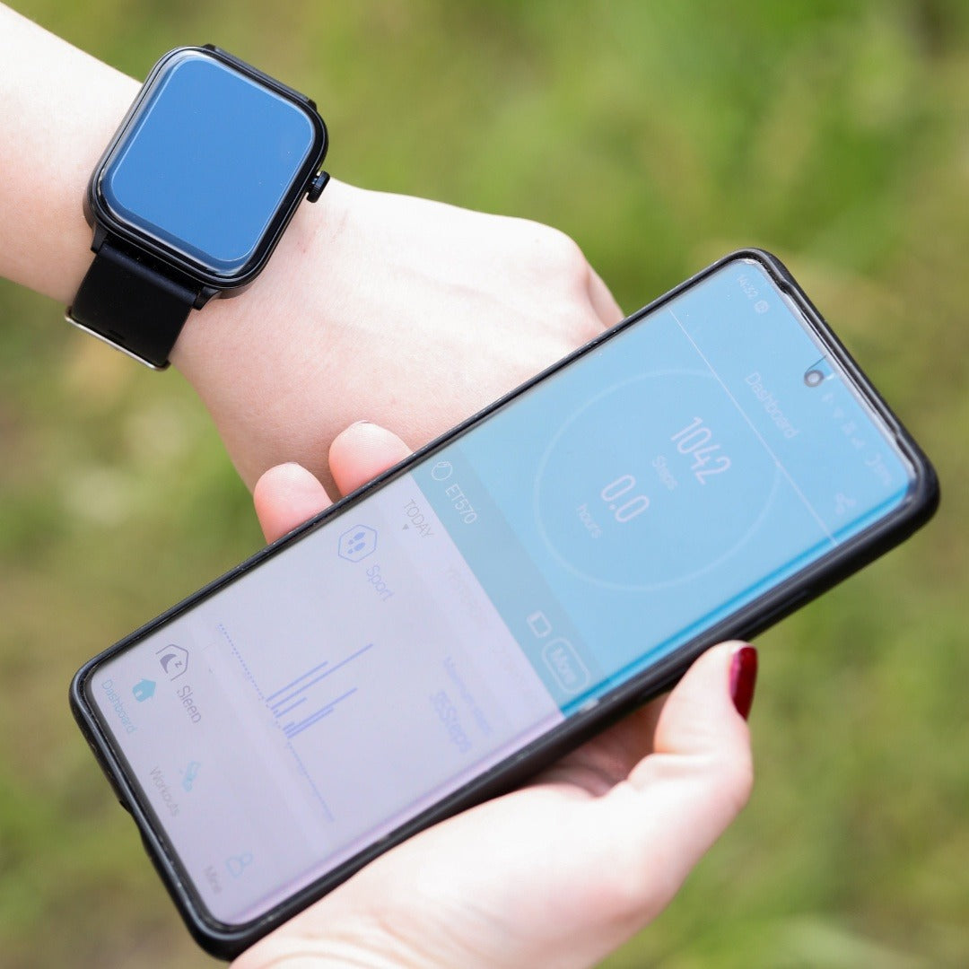 Smartwatch met blauwe band naast een telefoon met de app