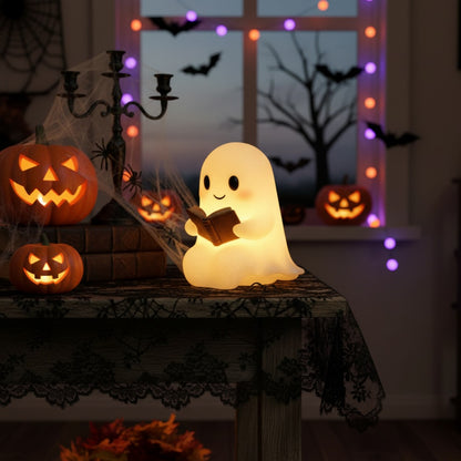 Wit spooklampje met zwarte oogjes en roze wangen dat een open bruin boek vasthoudt en warm geel oplicht