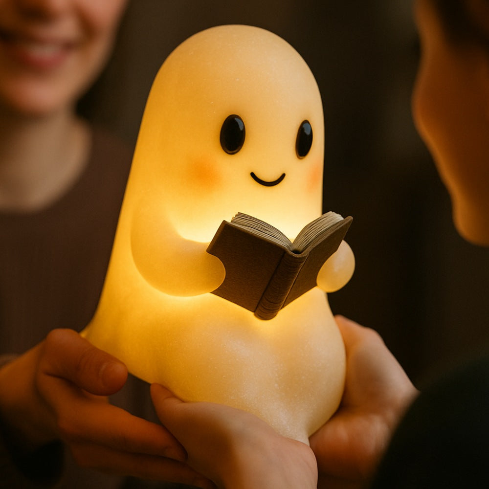 Wit spooklampje met zwarte oogjes en roze wangen dat een open bruin boek vasthoudt en warm geel oplicht