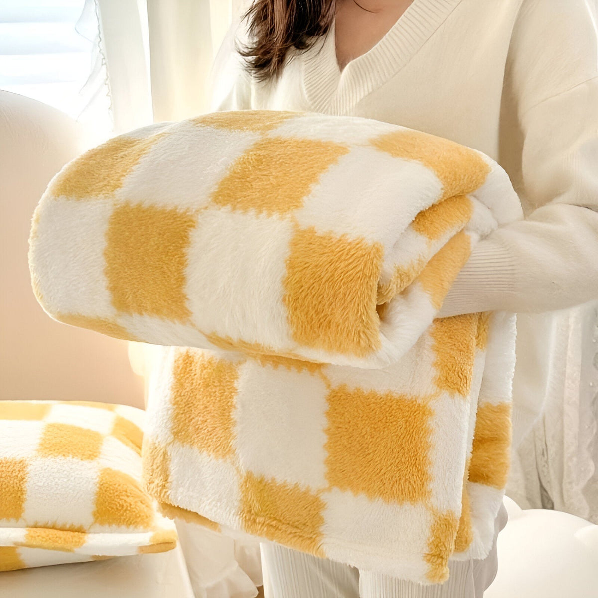 Teddy fleece deken met dambordpatroon, opgevouwen in de armen - okergeel